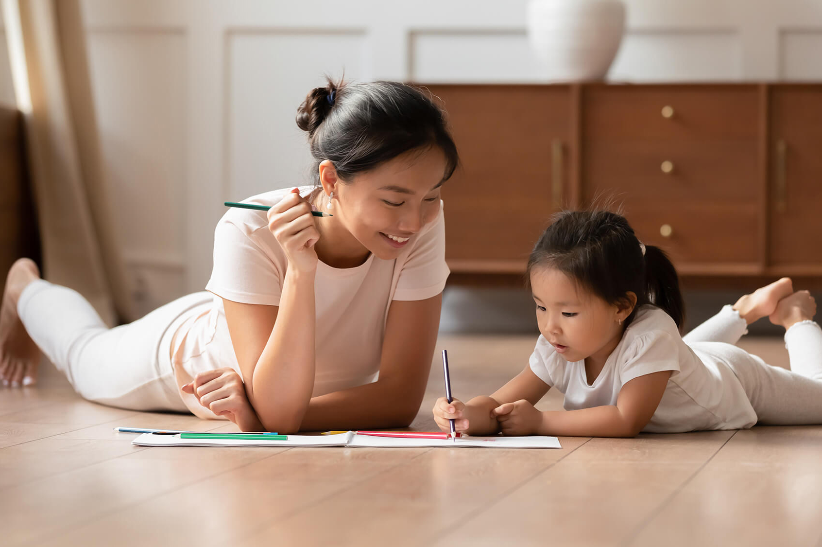 Young mom and little daughter painting at home