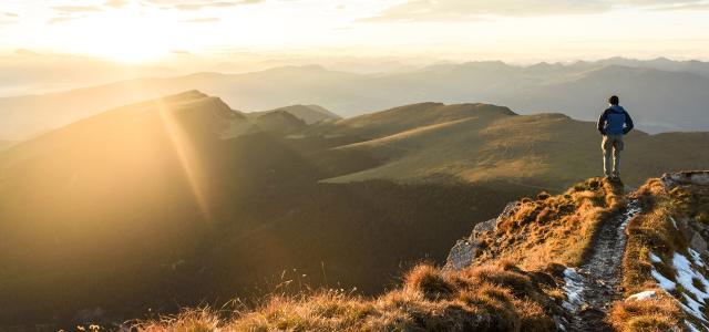 Silhouette of the man on top the peak of mountain on sunrise sky